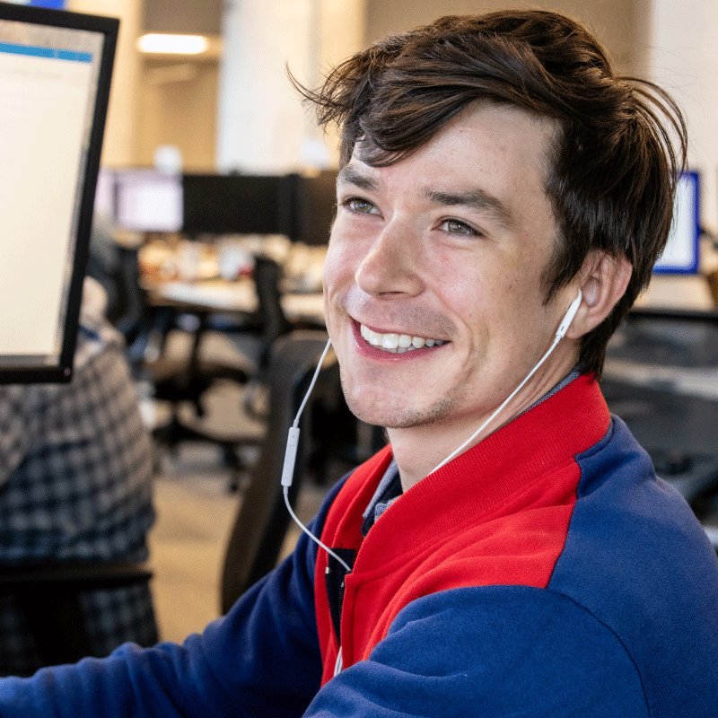 Echo employee smiling at computer screen with headphones in.
