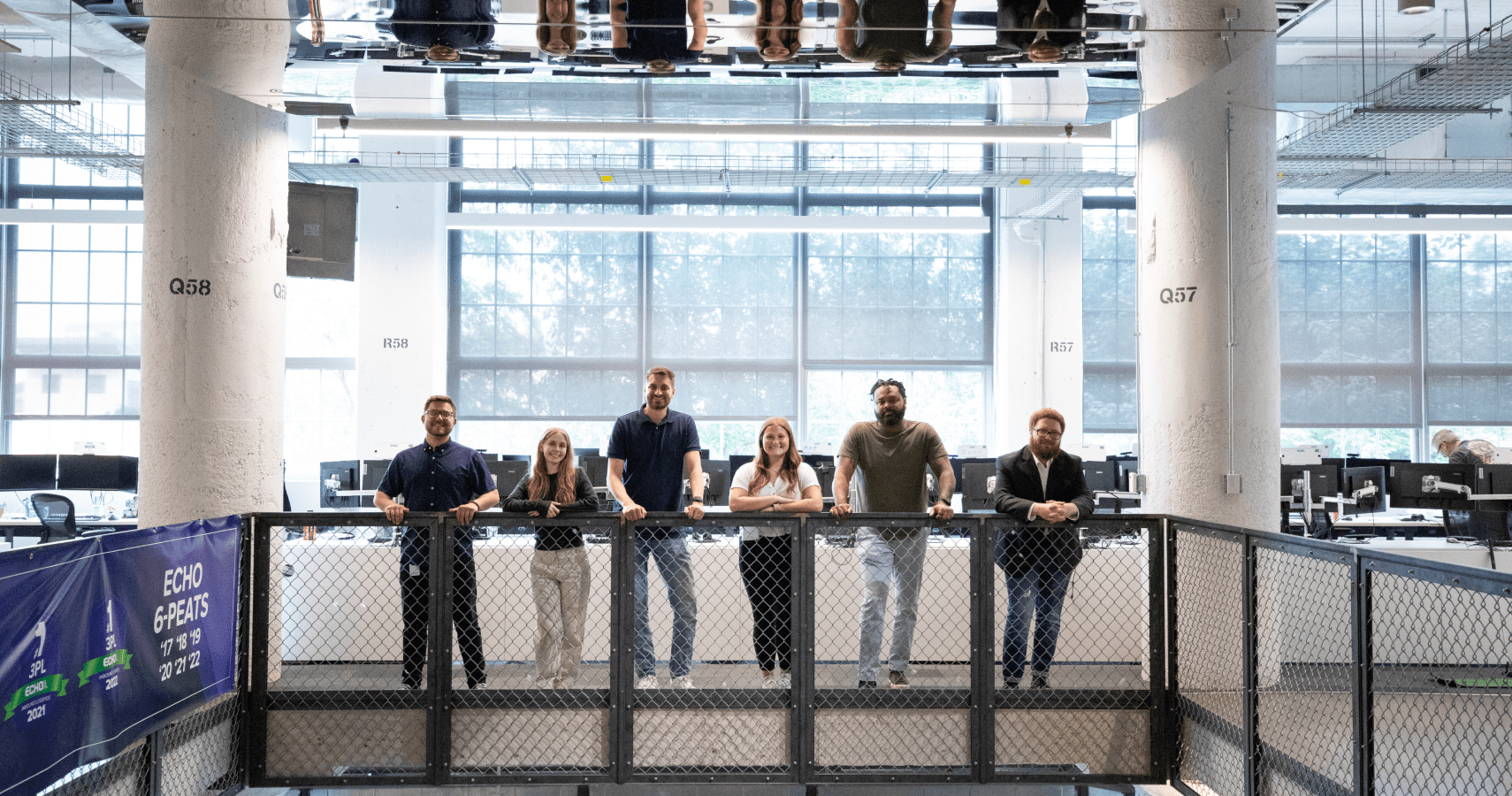 6 echo employees looking over banister at camera.