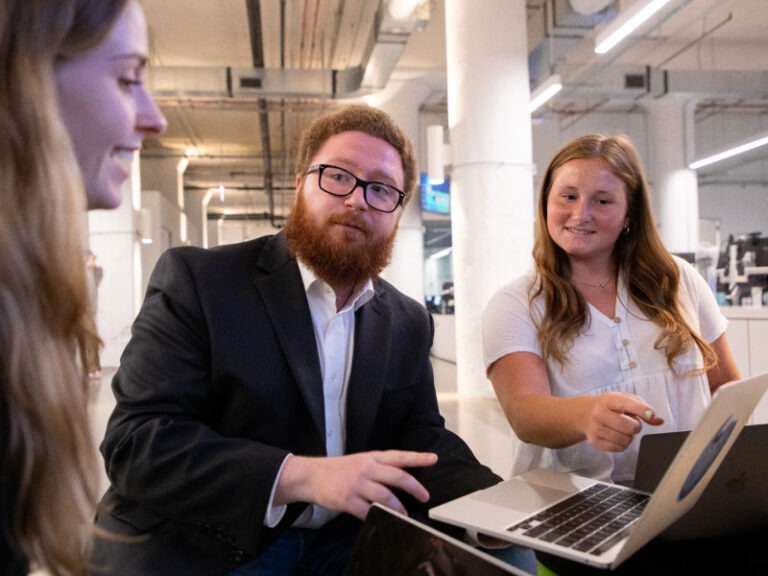 Three Echo employees huddled together while discussing a team project.