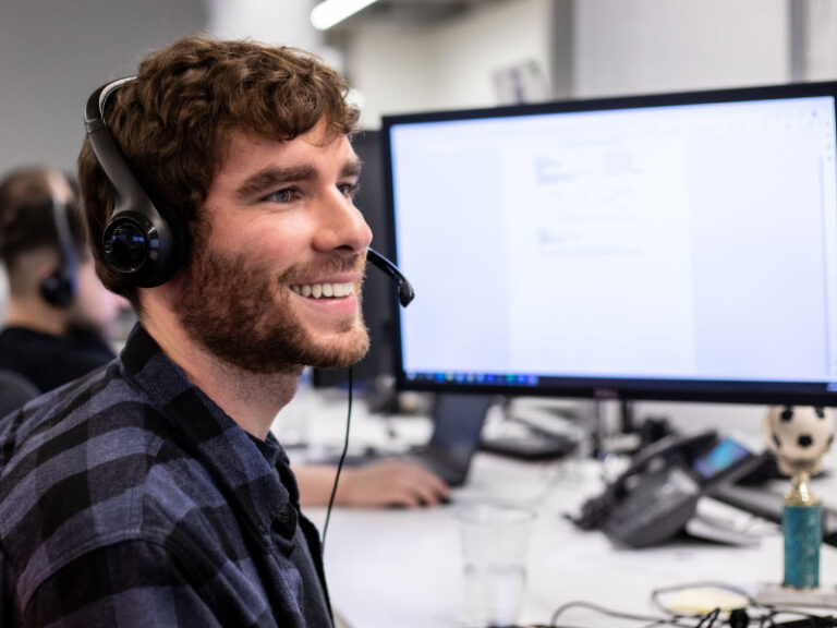 An Echo team member smiling at computer desk with headset on.