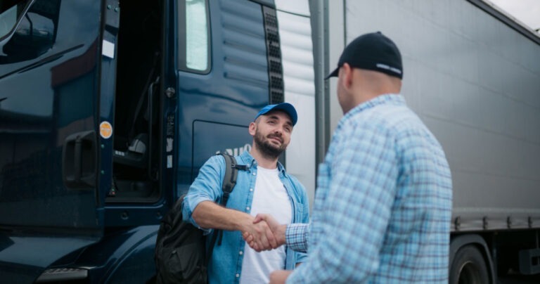 Two carriers shaking hands in front of truck.