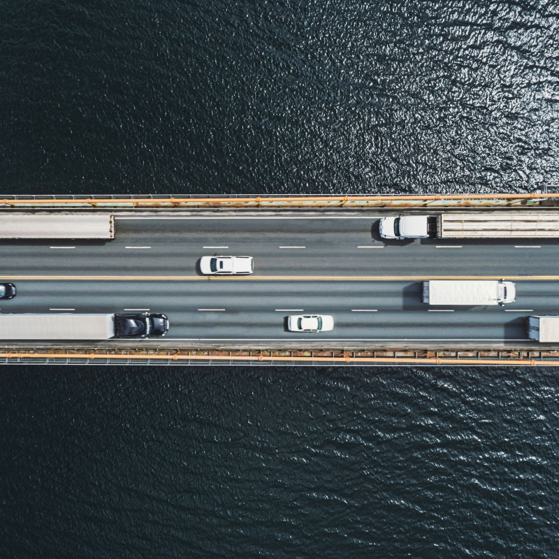 Vista aérea de un puente sobre una masa de agua con camiones y coches.