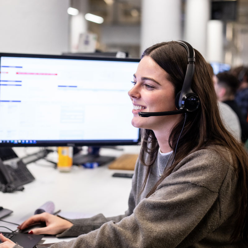An Echo employee smiling while wearing a headset and working at their computer.