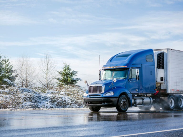 A long haul blue semi truck transporting cargo in refrigerator semi trailer during the winter time.