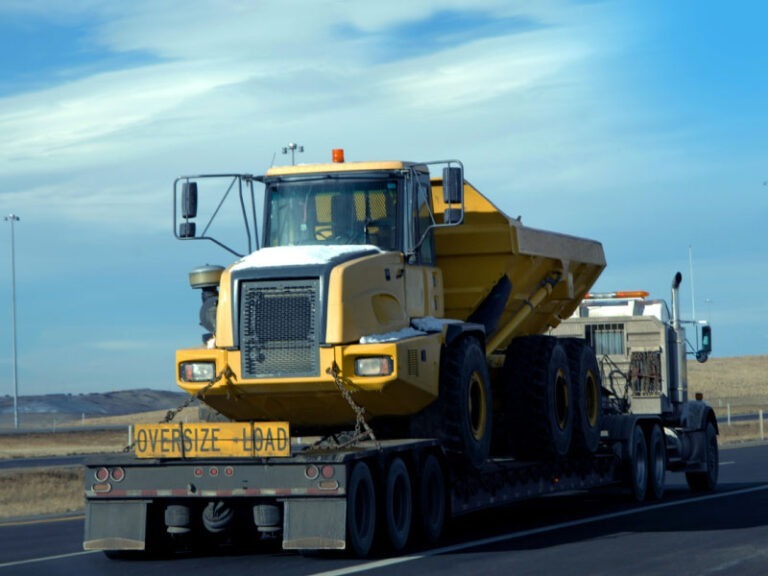 A semi truck transporting a heavy, oversized dump truck down the interstate.