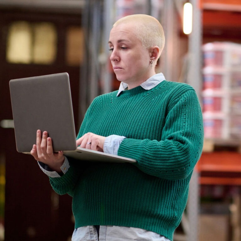 A warehouse manager on her laptop monitoring shipments that are coming in.