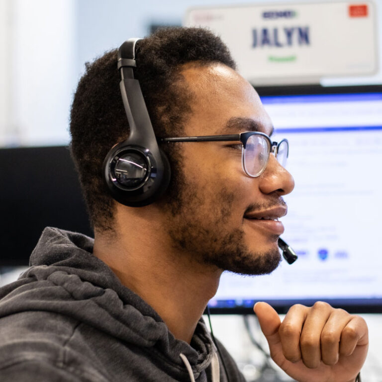 A smiling Echo employee on his computer helping clients with their freight scheduling.