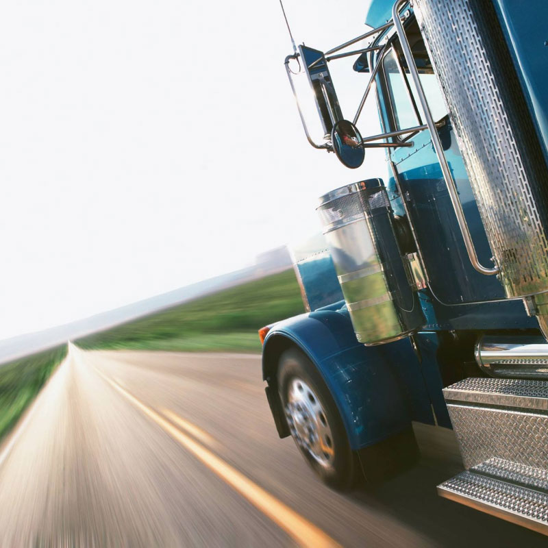 A blue Temp-Controlled truck driving down an open road during the day time.