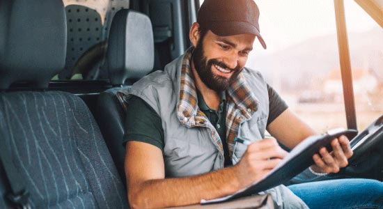 Truck driver looking at clipboard in cab of semi truck