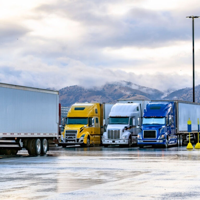 A blue, white, and yellow semi truck parked at truck stop parking lot.