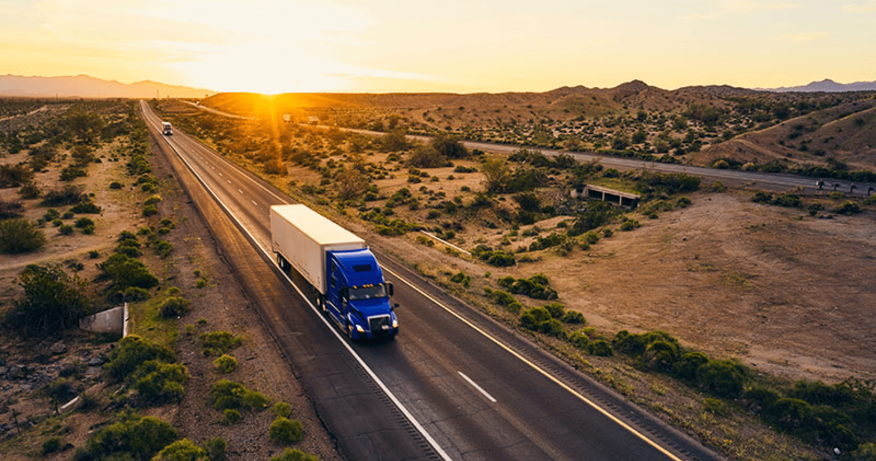 A blue semi truck driving on desert road.
