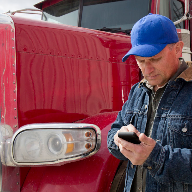 A truck driver on his phone outside of his truck