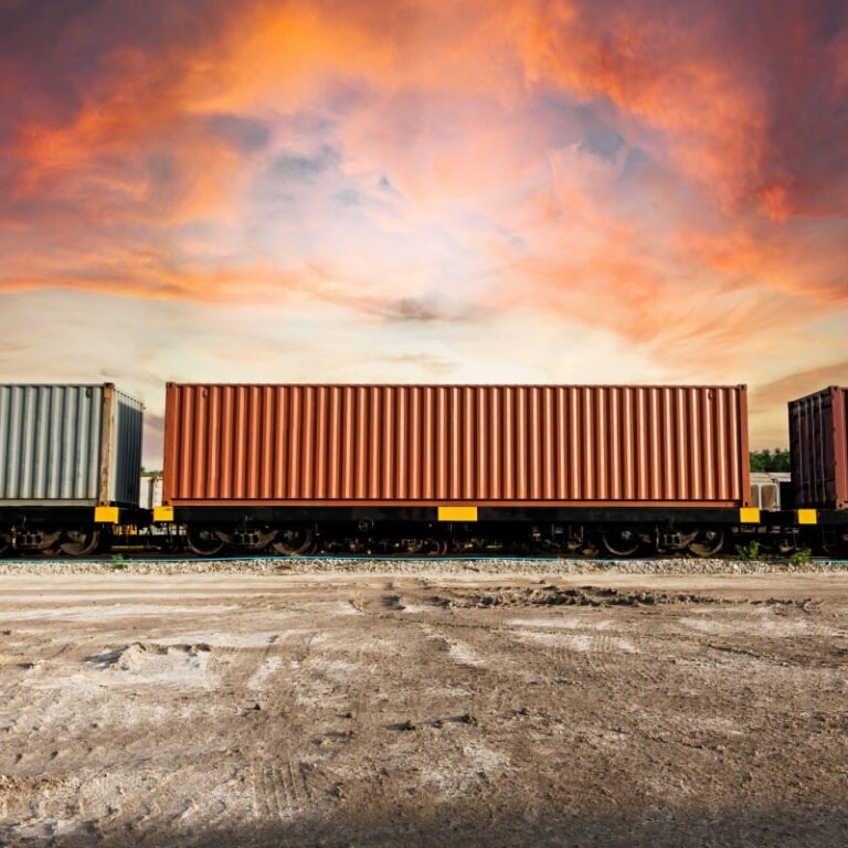 An intermodal shipping train carrying freight with a sunset backdrop.