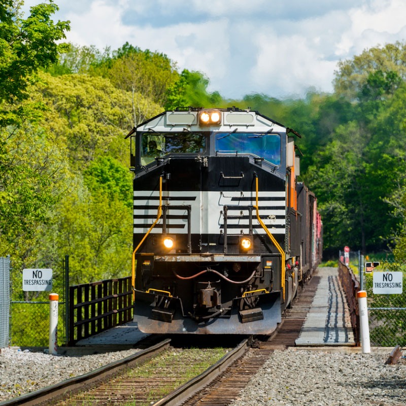 A black and white train crossing a railroad bridge carrying intermodal freight.