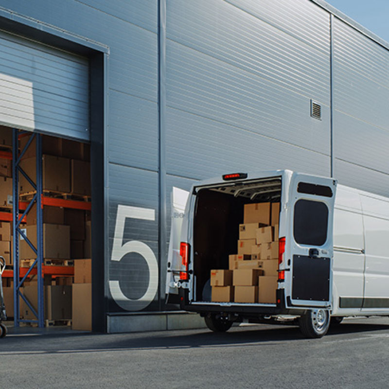 A small parcel delivery van being loaded with packages.