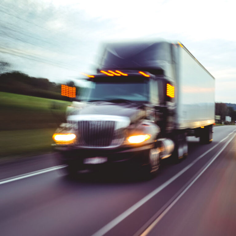 A semi truck driving fast down the highway on their way to their final destination.