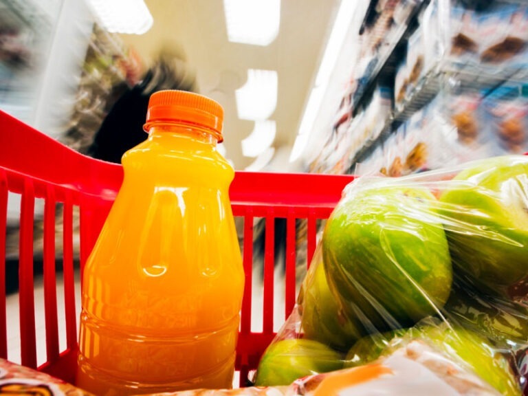 Motion-blurred supermarket seen from the inside of a moving grocery basket.