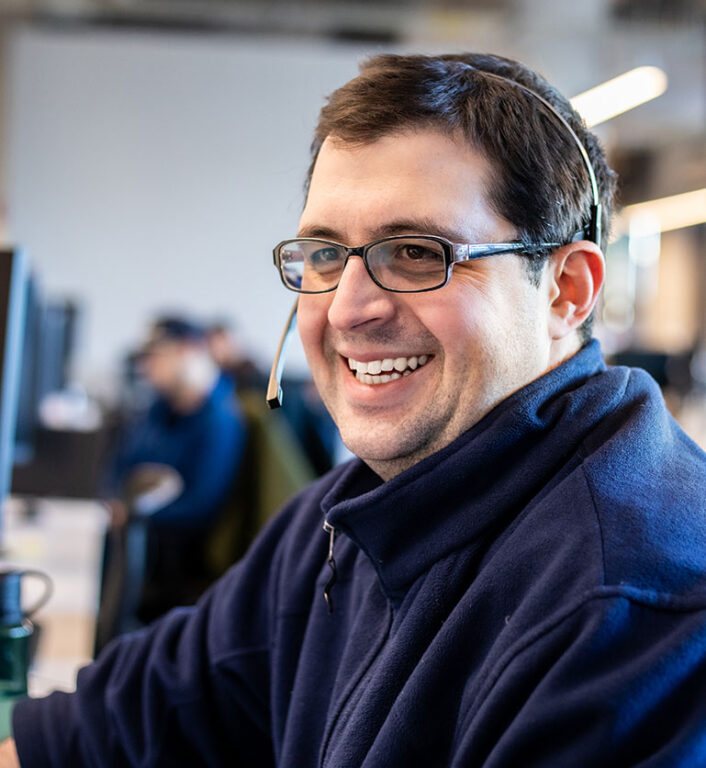 An Echo employee, with a headset on, smiling while working at desk in the office.