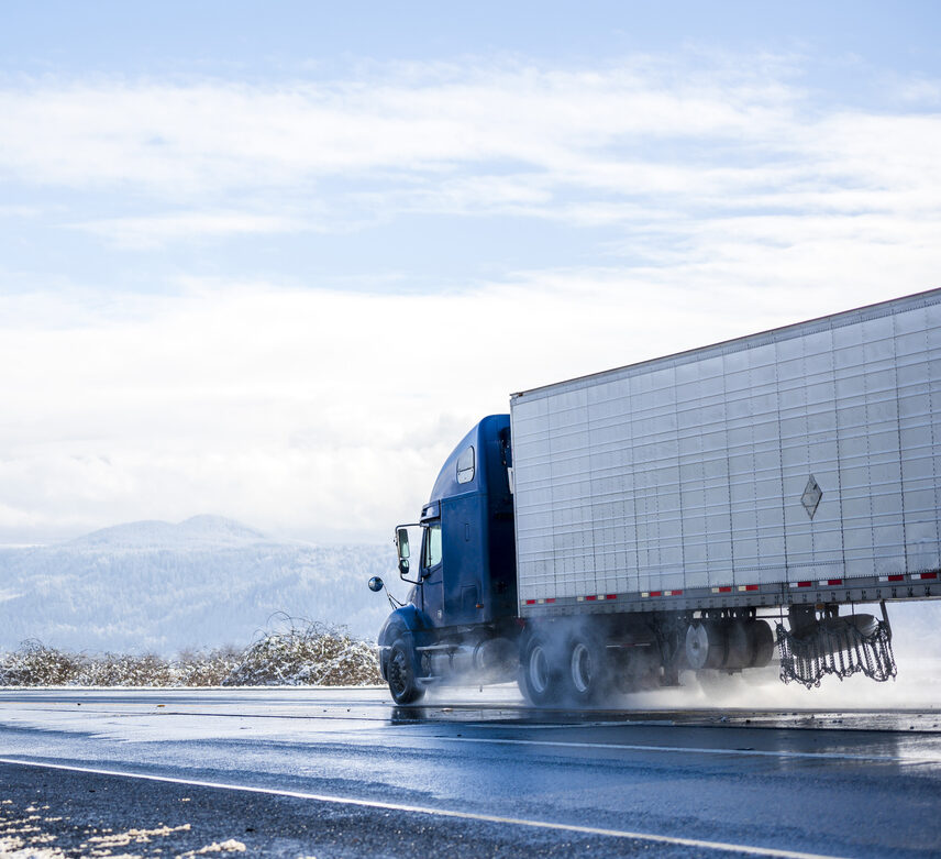 Blue semi truck with reefer semi trailer driving on the road transporting perishable products.