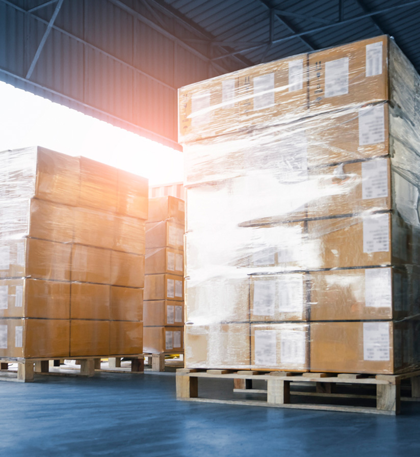 Stacked consolidated shipments waiting to be loaded onto a semi-truck at a freight loading dock.