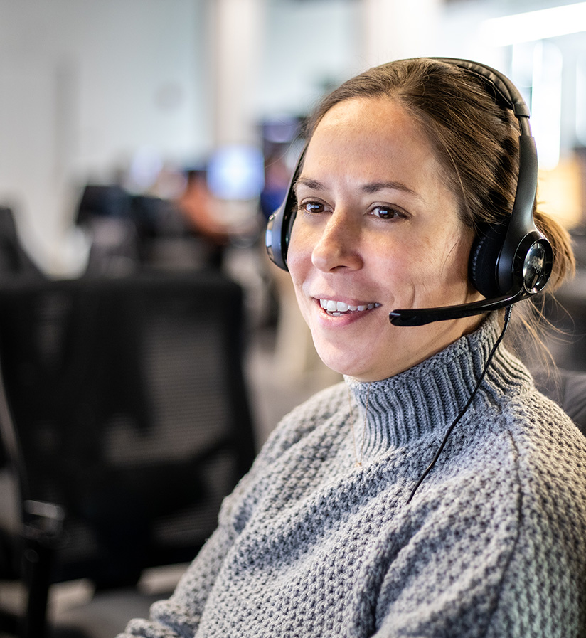 An Echo employee with a headset on smiling at their desk.