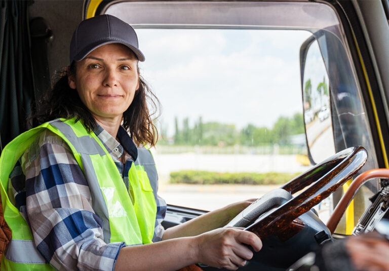 A female truck driver sitting in semi truck.