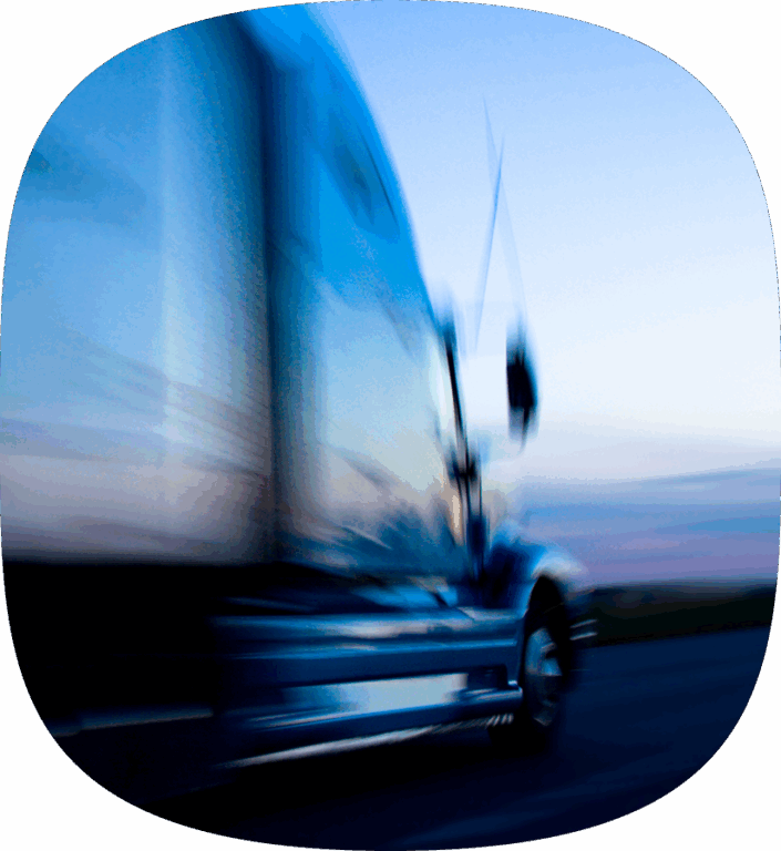 A semi truck driving down the highway very fast.