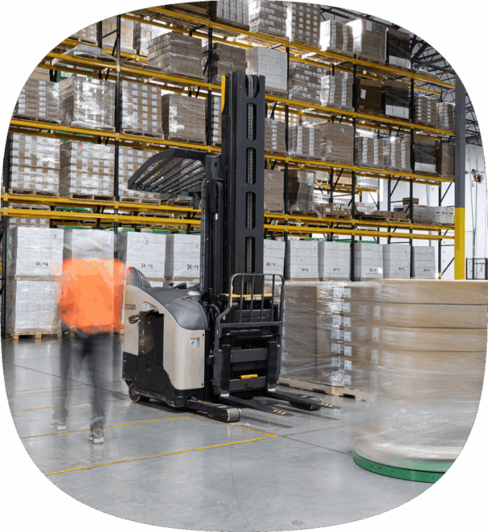 A stretch-wrap machine securing palletized freight with plastic film inside a warehouse before it’s prepared for shipment.