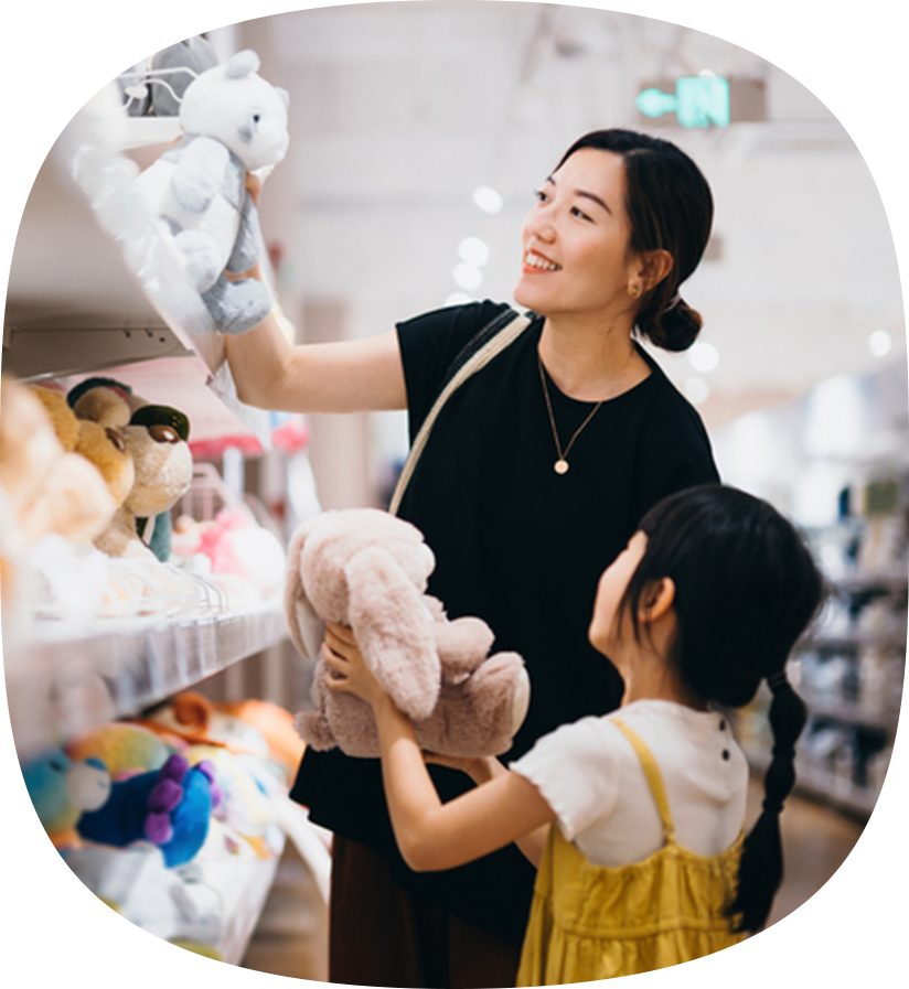 A women and child at the store picking a stuffed bunny off the shelf.
