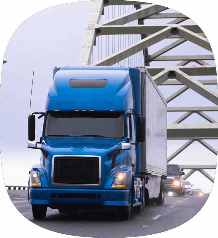 A blue semi truck driving down the highway to delivery CPG products. 