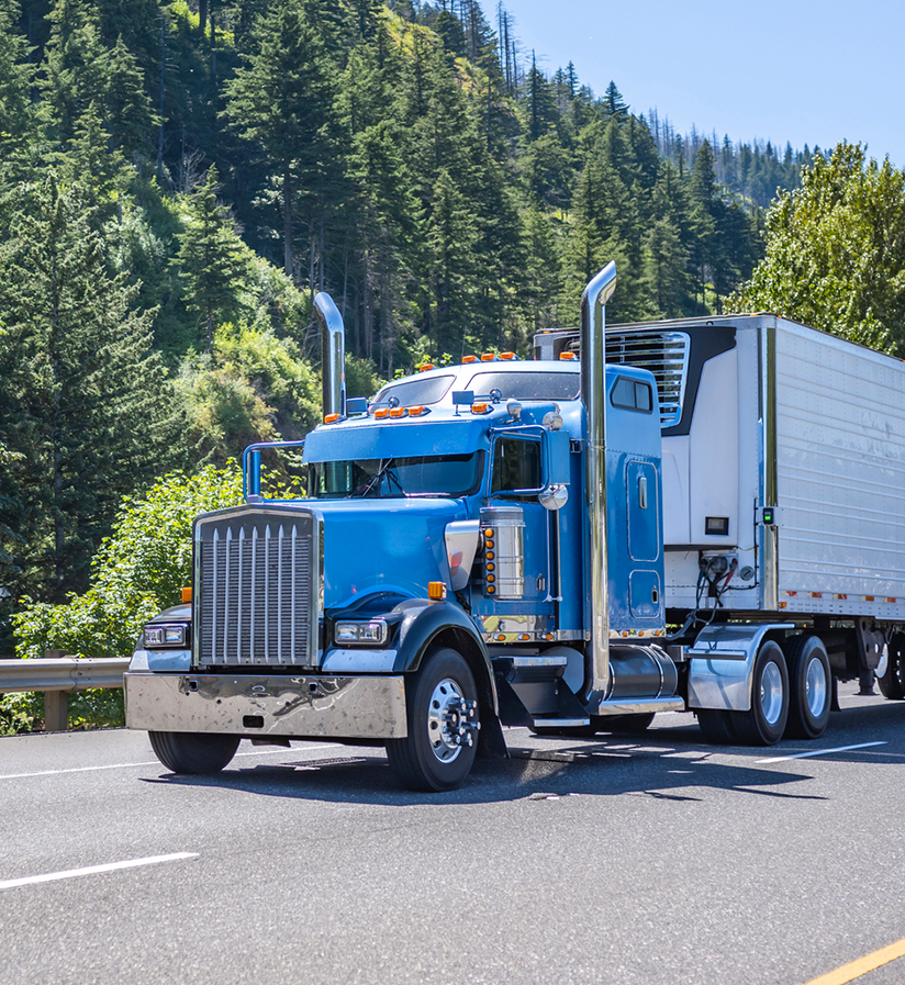 A blue semi truck driving down the highway. 