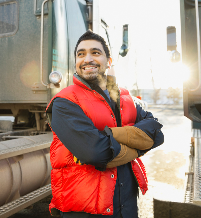 A smiling carrier standing in front of a semi truck.