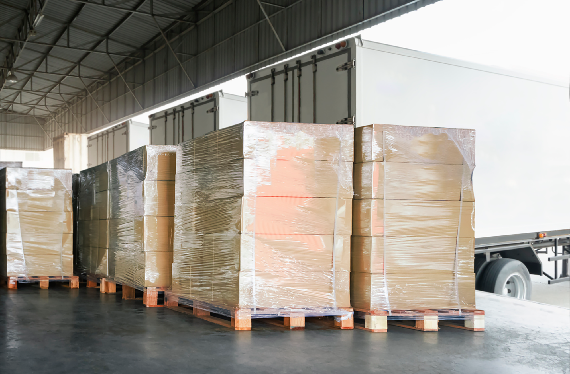 Stacked LTL shipments waiting to be loaded onto a semi-truck at a freight loading dock.